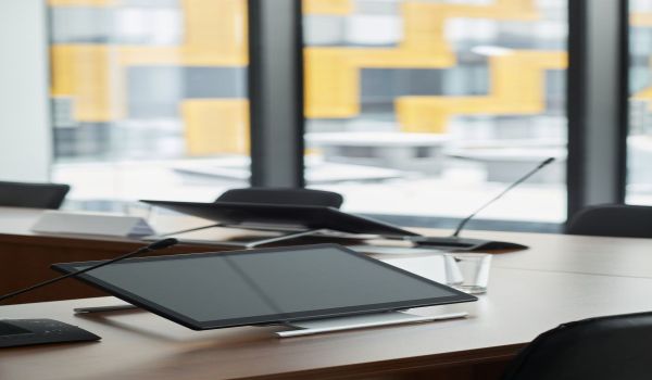 Услуги A sleek, modern office workspace with digital tablets and microphones on a conference table.