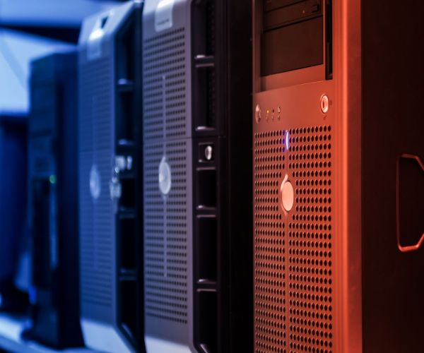 О Нас Close-up of tower servers in a data center with blue and red lighting.