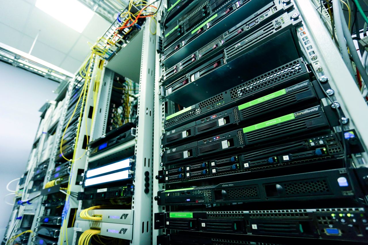 О Нас High-tech server rack in a secure data center with network cables and hardware components.